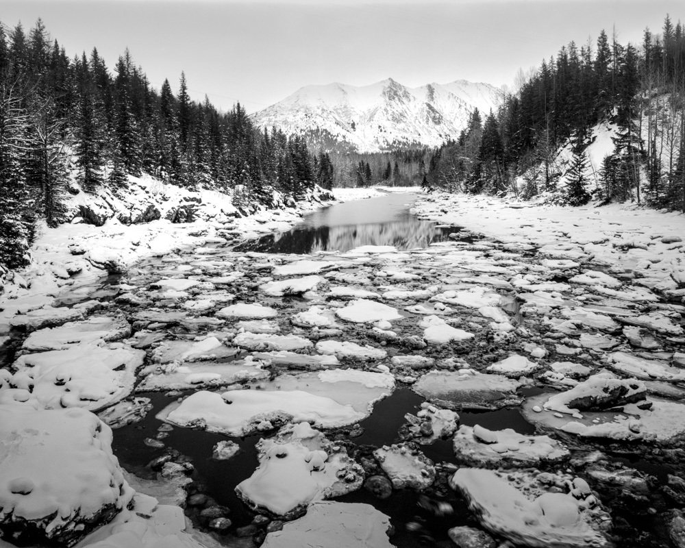 Picture of ice floes on a winter river in Alaska with mountains in the background.